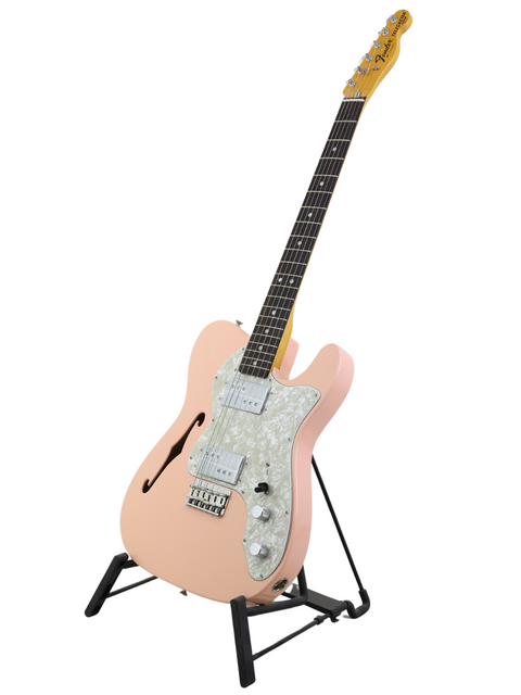 Peach-colored electric guitar on a stand against a white background.