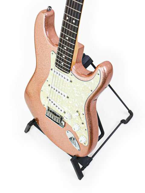 Pink Fender Stratocaster guitar from 1994 on a stand, set against a simple white background.
