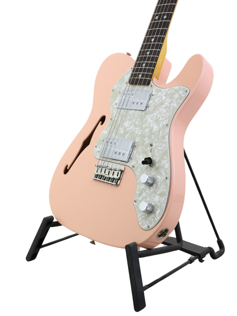 Pink electric guitar with white pickguard on a black stand against a white background.