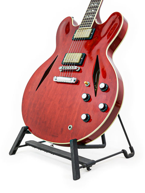 Red Gibson Custom Shop Trini Lopez guitar on a stand against a clean white background, showcasing its stunning design.