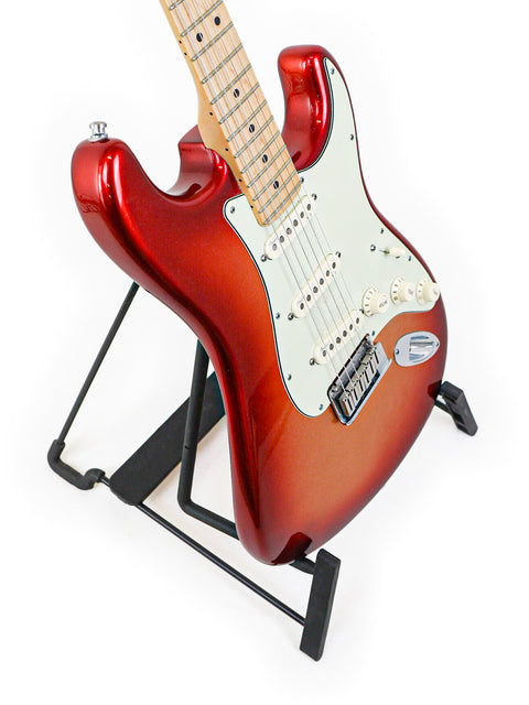 Red electric guitar on a black stand against a white background.