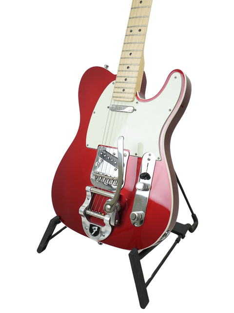 Red electric guitar with a white pickguard on a stand, isolated on a white background.