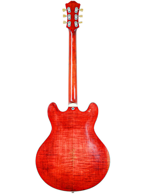 Red electric guitar with a wooden texture and six tuning pegs, isolated on a white background.