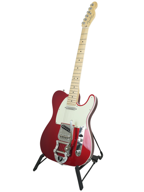 Red electric guitar with white pickguard on a black stand, isolated on a white background.
