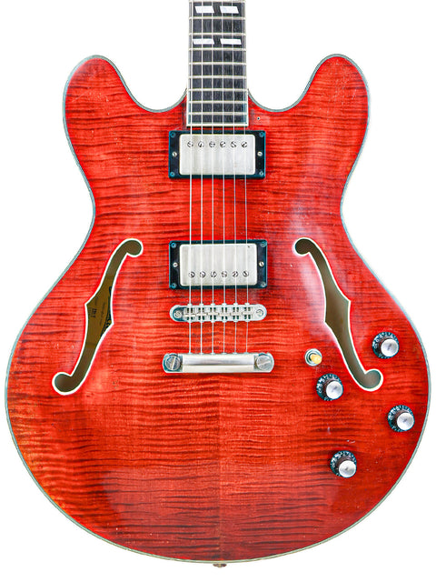 Red semi-hollow electric guitar with f-holes and dual pickups on a white background.