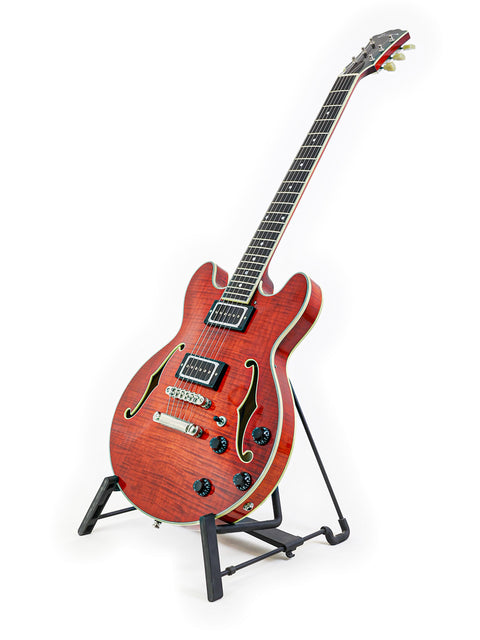 Red sunburst electric guitar on a stand against a white background.
