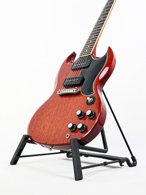 Red vintage Gibson SG Special guitar from 1964/5, showcased on a stand with a clean white backdrop.