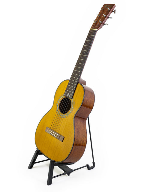 Small guitar on a stand, white backdrop, Martin Sting Mini Signature Edition #35 of 100, signed by Sting, USA 2005.