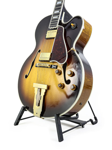 Stunning Gibson L-5 CES guitar displayed on a stand, set against a pristine white backdrop. A true classic from 2002.