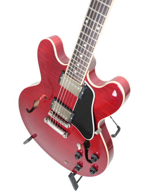 Stunning red electric guitar, the Gibson ES-335 Dot from 2006, elegantly positioned on a black stand.
