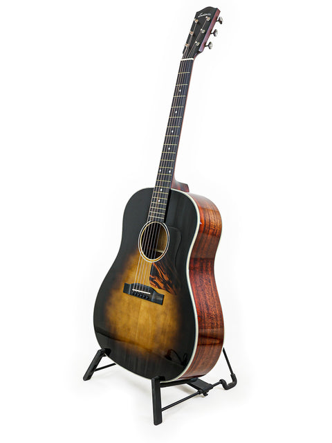 Sunburst acoustic guitar on a black stand against a white background.