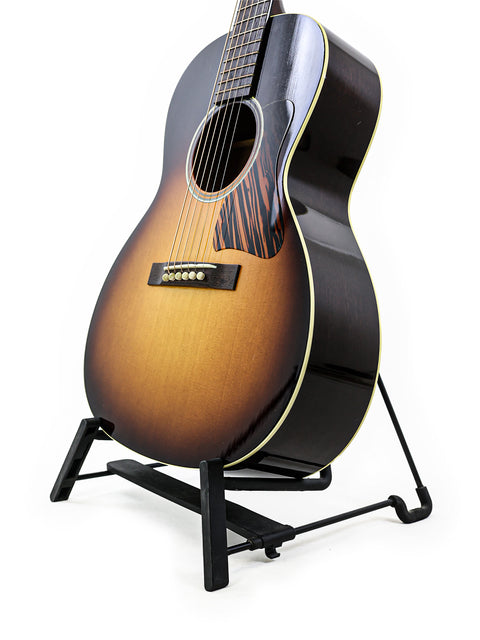 Sunburst acoustic guitar on a black stand against a white background.
