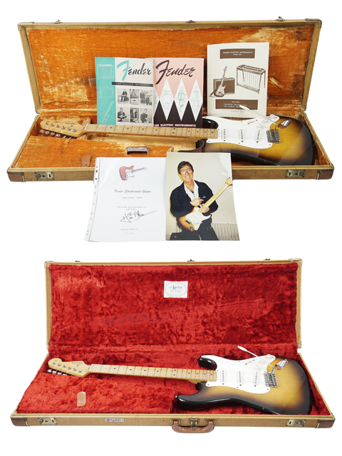 Classic 1957 Fender Stratocaster on a stand, elegantly displayed against a bright white background.