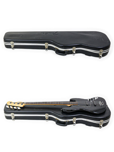 Two bass guitars in black cases, featuring Fender Jazz Bass models from 2005, set against a white backdrop.