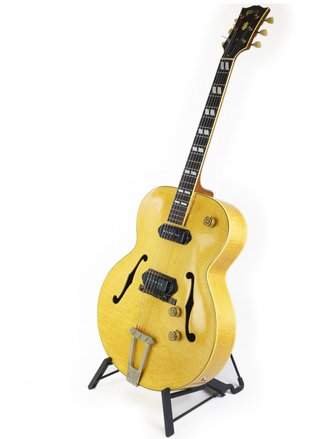 Vintage 1952 Gibson ES-300 guitar in yellow, beautifully positioned on a stand with a bright white background for contrast.