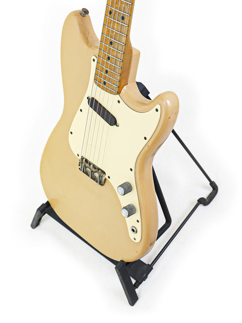 Vintage 1957 Fender Musicmaster electric guitar in beige, beautifully positioned on a stand.