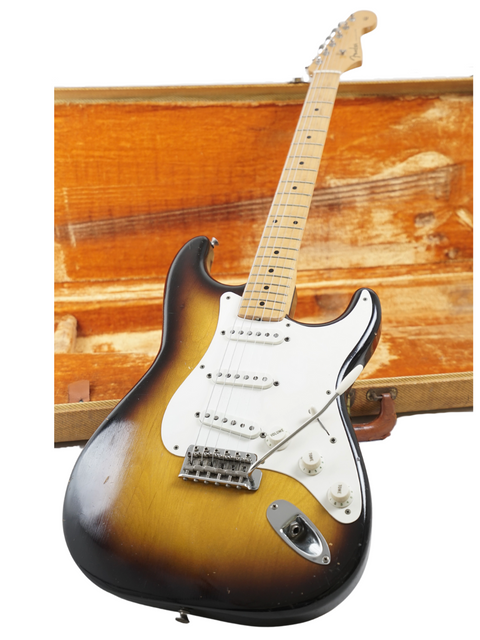 Vintage 1957 Fender Stratocaster guitar resting in a wooden case, a true collector's item with a rich history.