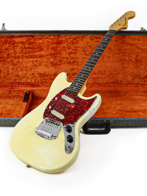 Vintage 1967 Fender Mustang guitar in white, beautifully displayed in a vivid orange case, a true collector's item.