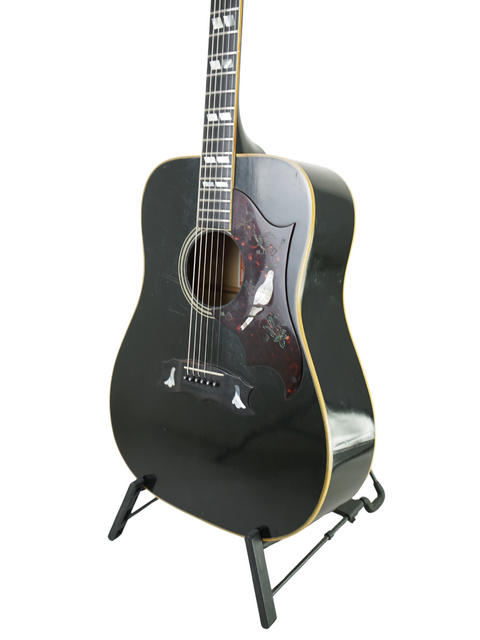 Vintage 1977 Gibson Dove Custom acoustic guitar in black, beautifully showcased on a stand, highlighting its timeless design.
