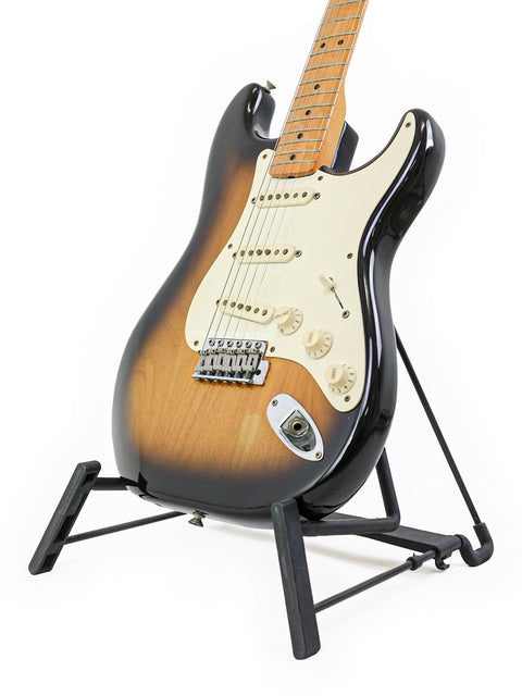 Vintage 1982 Fender AVRI ‘57 Stratocaster resting on a stand, highlighted by a bright white background.