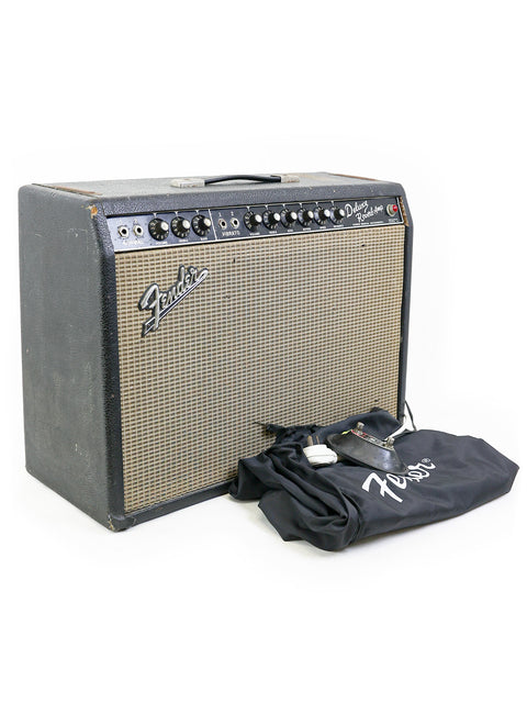 Vintage Fender Deluxe Reverb amp from 1965, paired with a guitar and bag, ready for jamming or showcasing.