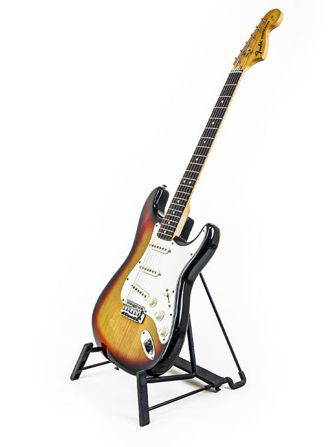 Vintage Fender Stratocaster from 1974 elegantly positioned on a stand, highlighted by a simple white background.
