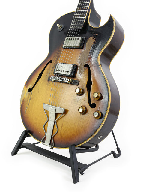 Vintage Gibson ES-175D guitar resting on a stand, set against a bright white background.