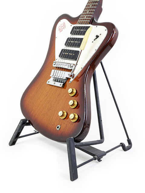 Vintage Gibson Non Reverse Firebird III guitar from 1966 on a stand, emphasizing its iconic shape and rich history.