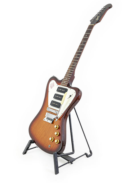 Vintage Gibson Non Reverse Firebird III guitar from 1966 resting on a stand, set against a white background.