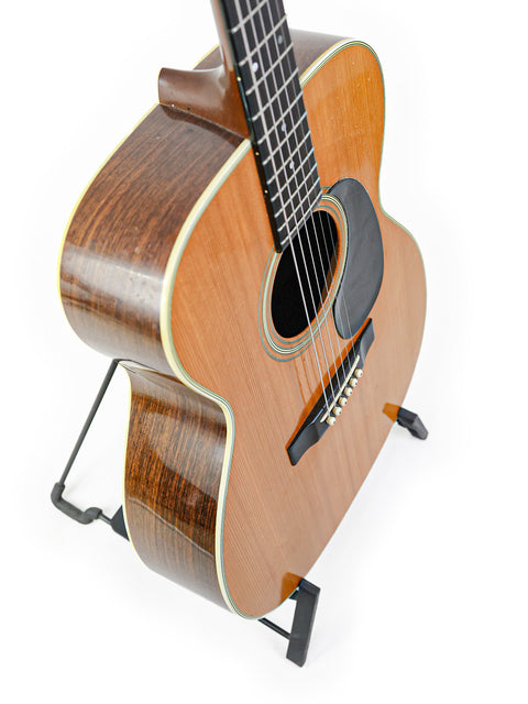 Vintage Martin 000-28 guitar from 1976 elegantly positioned on a stand with a stark white background.