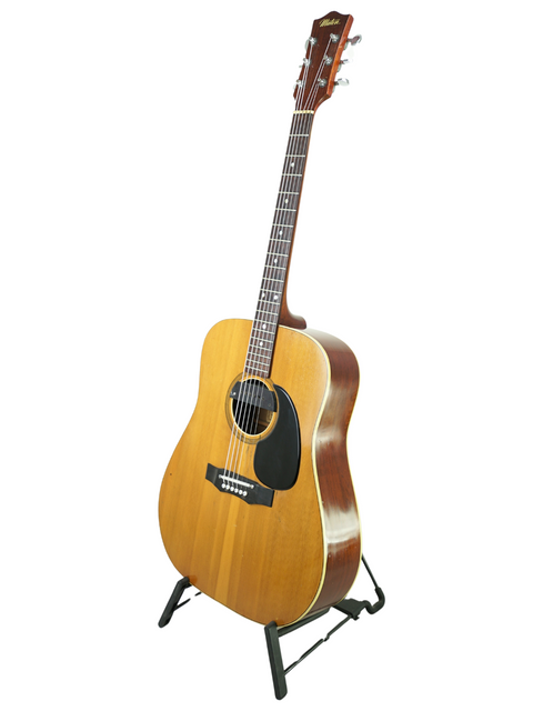 Vintage Maton FG100 guitar from 1972 resting on a stand, highlighted by a simple white background.
