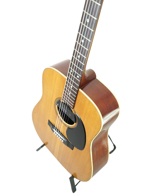 Vintage Maton FG100 guitar from 1972 resting on a stand, with a simple white background emphasizing its timeless style.
