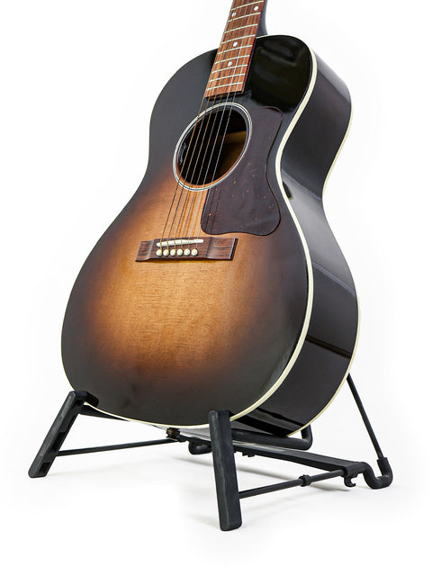 Vintage Sunburst Gibson L-00 Standard guitar displayed on a sleek black stand, highlighting its classic appeal and quality.
