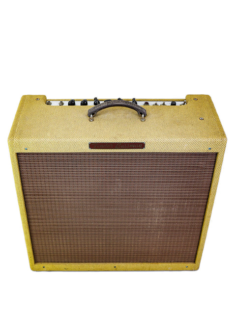 Vintage guitar amplifier with a yellow tweed cover and control knobs on top.