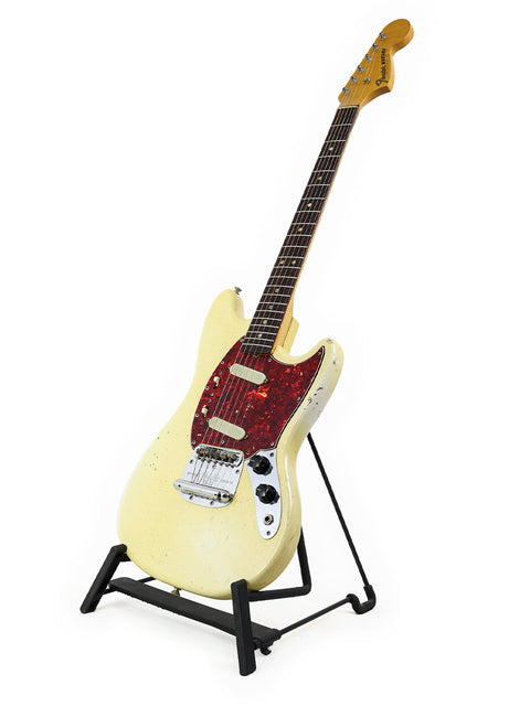White 1967 Fender Mustang guitar resting on a black stand, a perfect blend of vintage style and musical heritage.