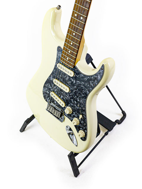 White Fender Jeff Beck Signature Stratocaster guitar featuring a black pick guard, elegantly positioned on a stand.

