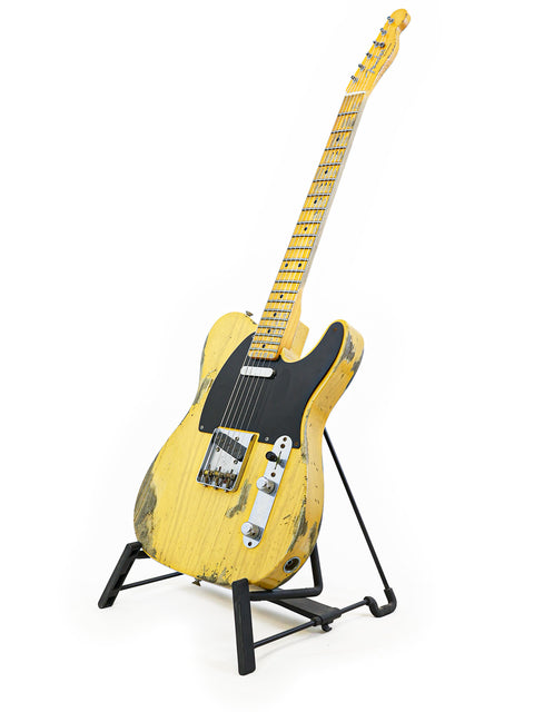 Yellow Fender Custom Shop '53 Telecaster Heavy Relic guitar elegantly positioned on a stand with a contrasting black base.