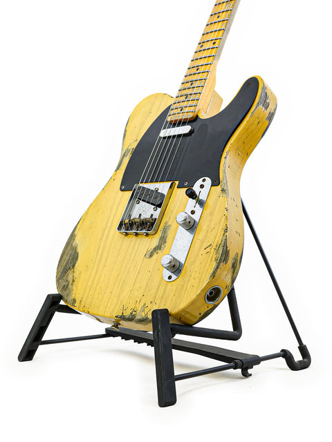 Yellow Fender Custom Shop '53 Telecaster Heavy Relic guitar on a stand featuring a sleek black base.
