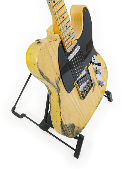 Yellow Fender Custom Shop '53 Telecaster Heavy Relic guitar resting on a black base stand, showcasing its vintage design.
