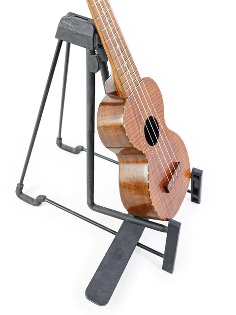 classic Kumalae ukulele from the 1920s rests on a stand, reflecting its historical significance in Hawaiian culture.
