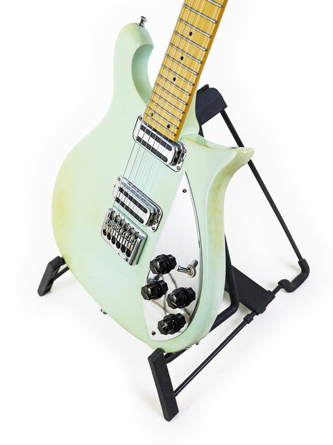 green Rickenbacker 650C Colorado electric guitar from 2005 displayed on a stand, showcasing its vibrant color and design.
