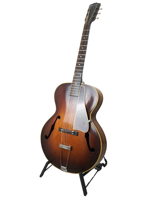vintage 1938 Kalamazoo KG-32 guitar elegantly positioned on a stand, set against a pristine white backdrop.