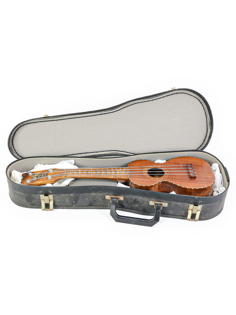 vintage Kumalae ukulele from the 1920s resting in its case against a clean white background.