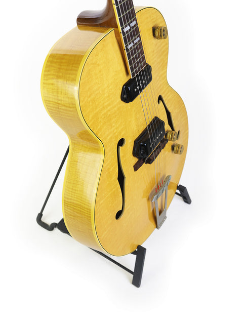 1952 Gibson ES-300 guitar on a stand, featuring a minimalist white background that emphasizes its vintage charm.