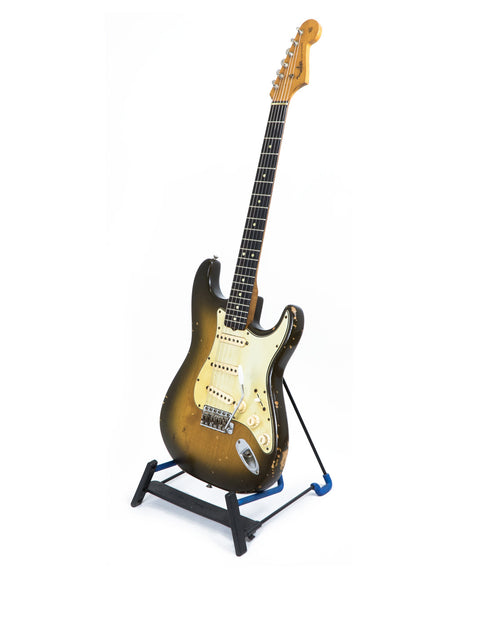 1963 USA L Series Stratocaster guitar resting on a stand, set against a plain white background.