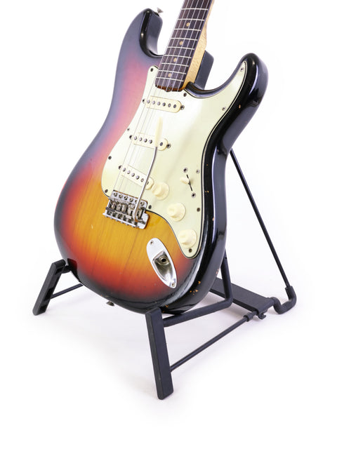 1964 Fender L Series Stratocaster guitar on a stand, highlighted by a crisp white background.