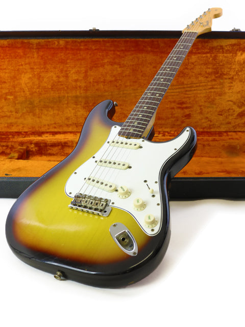 1965 USA Fender Stratocaster with a vibrant sunburst finish, elegantly displayed in its wooden case.