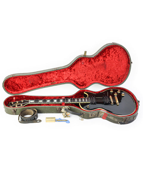 1969 vintage Gibson Les Paul Custom in black, protected by a bright red case.