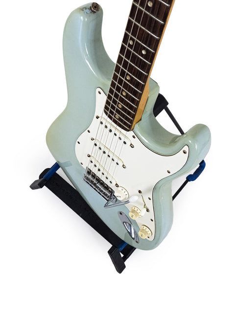 1972 vintage Fender Stratocaster guitar displayed on a stand with a striking blue backdrop, labeled as sold.
