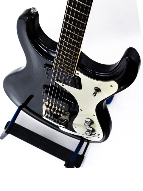 1990s black Mosrite guitar on a stand, set against a stark white background, highlighting its classic design.